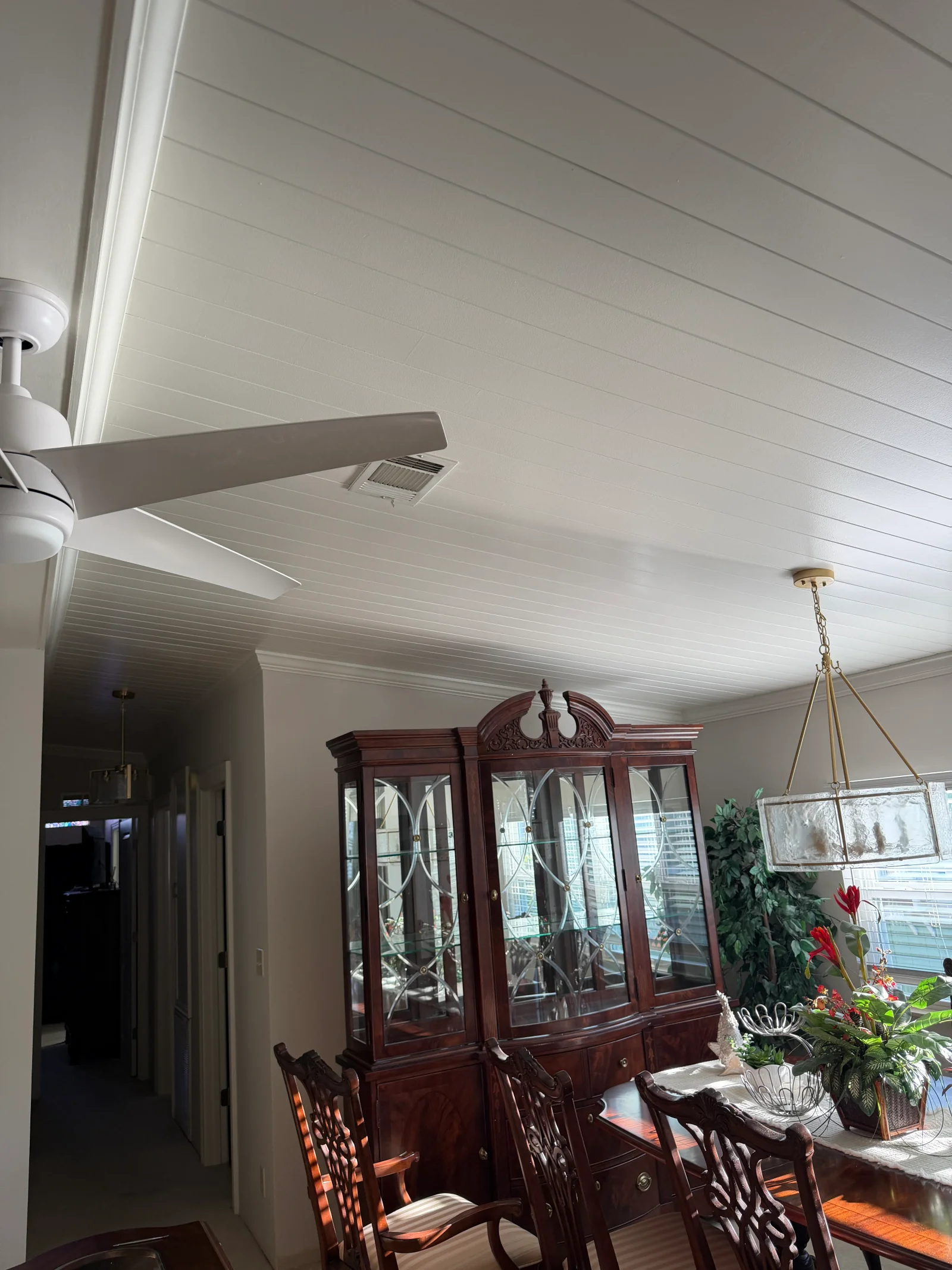 White painted shiplap ceiling with horizontal boards, crown molding, and ceiling fan in a dining room